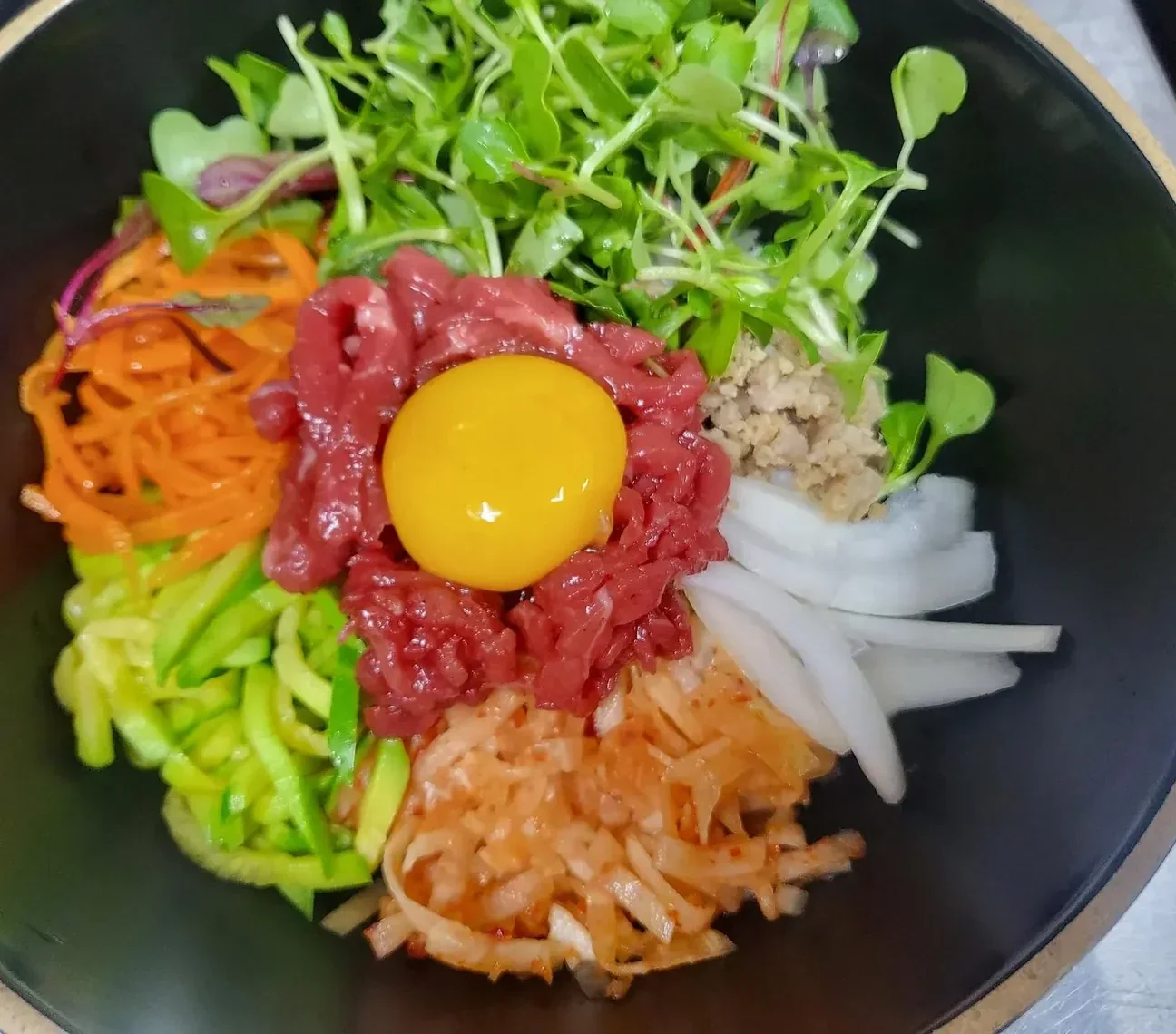 A Korean bibimbap bowl with egg, beef and seasoned vegetables